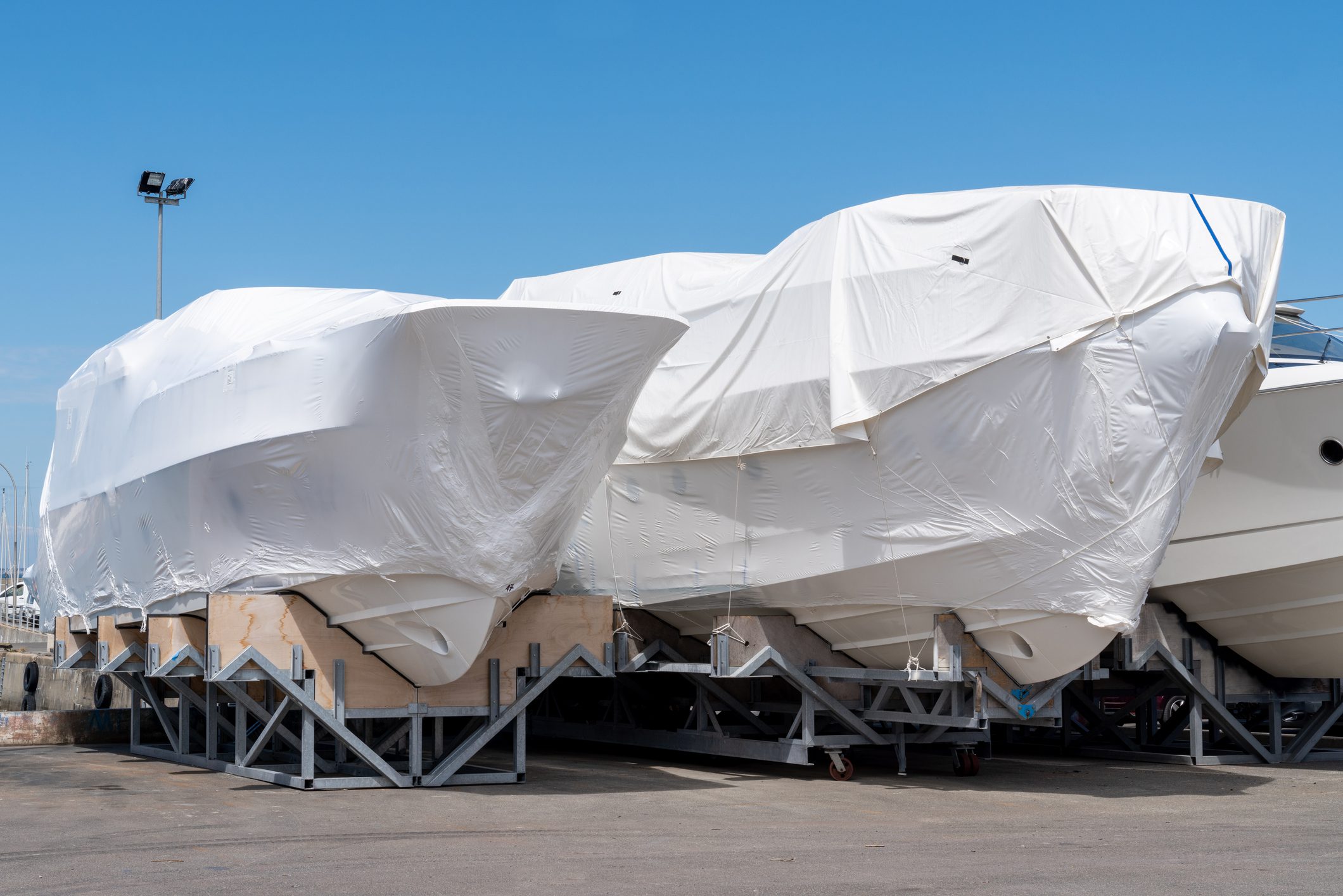 Covered boats on dry dock under sky.