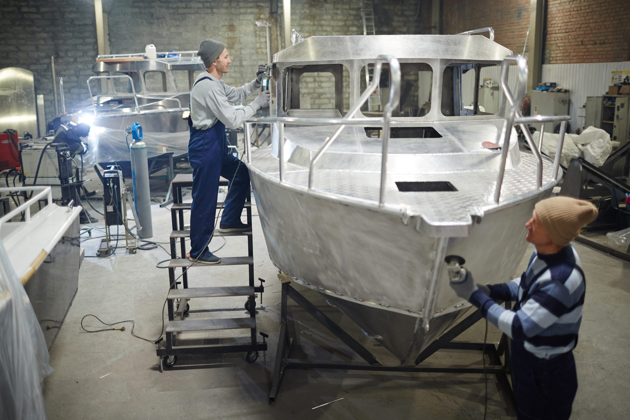 Workers assembling aluminum boats in workshop.